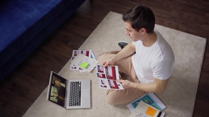 Wall Mural - top view of creative young man discussing ideas and notes with two colleagues during video conferenc
