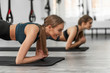 © Тарас Нагирняк - Healthy lifestyle. Portrait of two young sportive girls doing plank with trx fitness straps in the gym