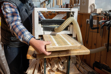 Senior craftsman woodworking at carpentry with lots of modern professional power tools. Man using thicknessing planer machine, clamp joiner, circular saw and other equipment at workshop.hobby concept