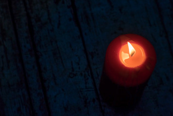 Candle lit. Beautiful red holiday candle, on wooden background. Christmas, Easter.