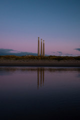 Wall Mural - reflection of smokestacks in water during sunset