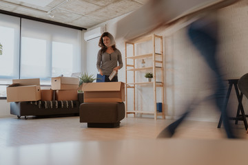 Wall Mural - Photo of good looking brunette unpacking boxes on moving day. Young woman is moving in to new home.