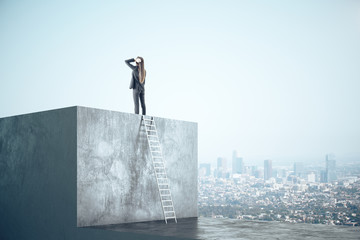 Wall Mural - Businesswoman standing on concrete cube and look into the distance