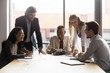 © fizkes - Excited diverse coworkers sit at office desk laugh have fun discussing paperwork at meeting together, overjoyed businesspeople gather at table in boardroom joke smile brainstorming at meeting