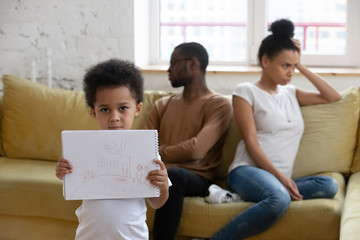 Sticker - Close up african american boy suffering from parents conflict at home in living room and holding picture. Sad son frustrating hear mother and father fighting arguing, family conflict, divorce.