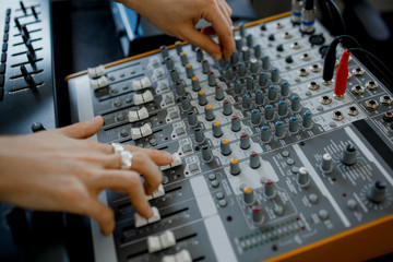 Hand on a mixer, operating the leader. Sound engineer working at mixing panel in the recording studio. Hands adjusting audio mixer. Close up concept.