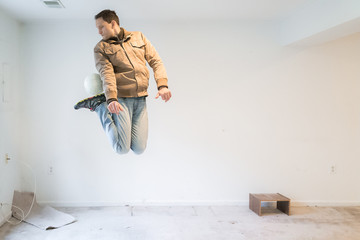 Wall Mural - Young skilled man jumping up performing mid-air trick with soccer ball playing sports inside dirty basement room in house, empty stains, old carpet