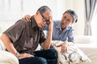 © Kawee - Asian senior old man having headache stress problem put hand on temple sitting on sofa at home. Elder wife sit beside consoling husband put hug, put hand on shoulder. Make comfort talking to relax him