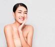 © Ann Patchanan - Beautiful young brunette posing,Youthful bright skin pretty Asian woman with clean and bright skin, Cosmetic Beauty Concept,hands touch on the cheek, smiling face isolated on grey background