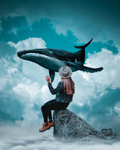 Digital Composite Image Of Young Woman Sitting On Rock With Fish In Mid-air