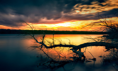 Wall Mural - Beautiful sunset clouds over the lake with silhouette trees and long exposure silky smooth water