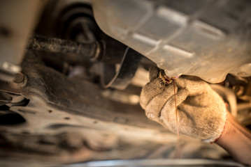 Wall Mural - Drain the old oil from the engine through the drain plug. Changing the oil in a car engine.