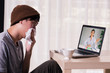 © twinsterphoto - Young Asian male patient with sickness using laptop to video call conferencing with doctor at home. Medical .consultation via internet connection. Telecommunication Healthcare concept.