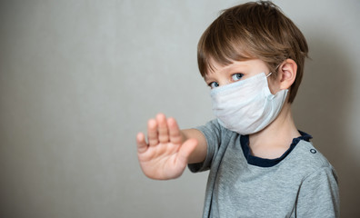 Child boy wearing a medical protective mask against the Coronavirus Covid 19, showing stop hands gesture to stop the infectious virus outbreak. Concept of stop infection epidemic virus symptoms