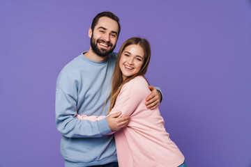 Wall Mural - happy young loving couple isolated over purple background.