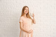 © Pixel-Shot - Beautiful pregnant woman with milk on white brick background