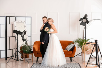 Wall Mural - Young wedding couple posing for photographer in studio