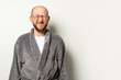 © Alex - Portrait of a young bald man with a beard in a dressing gown and glasses closed his eyes, squinted at an isolated light background. Emotional face