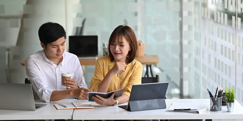 photo of business consulting team working together with computer tablet while sitting at the long wo