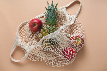 Wall Mural - top view flat lay string bag with pineapple and red apples on a beige background