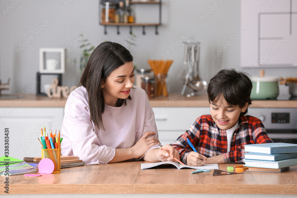 Little boy with his mother doing homework in kitchen
