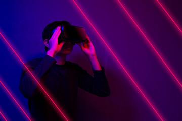 Asian man wearing the virtual reality goggles blue and magenta neon light scene