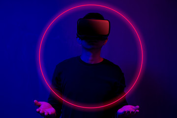 Asian man wearing the virtual reality goggles blue and magenta neon light scene