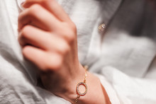 Gold Bracelet In The Form Of A Ring With Diamonds On A Chain, Girl’s Hand, Sleeve Of A White Shirt, Dark Background.
