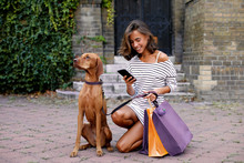 Young Woman Shopping With Her Dog Texting On The Phone