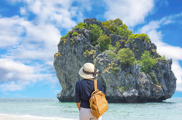 The image behind the woman wearing Hat and shoulder backpack Background Langkawi Island in sea and clouds in sky at Chumphon , Thailand. 