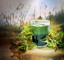 Green raw nettles and a smoothie made of nettles juice in  a glass