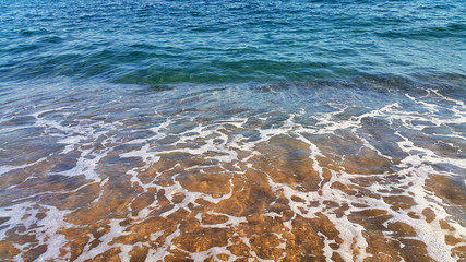 Wall Mural - Clear sea water with white foam in the coastal sand