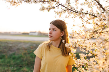 Portrait of young beautiful blonde woman near blooming tree with white flowers on a sunny day. Spring, girl near a flowering tree.beautiful girl in a yellow t-shirt near a flowering tree