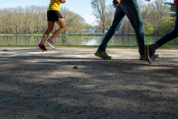  legs of a jogger and walking peolpe in a park, lake as background