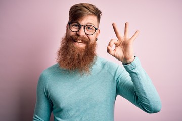 Poster - Handsome Irish redhead man with beard wearing glasses over pink isolated background smiling positive doing ok sign with hand and fingers. Successful expression.