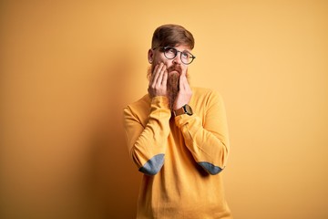 Poster - Handsome Irish redhead man with beard wearing glasses over yellow isolated background Tired hands covering face, depression and sadness, upset and irritated for problem