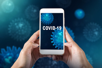 Hands holding a mobile phone with COVID-19 text on the screen