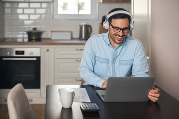 Wall Mural - Businessman listening music on headset while working on laptop.