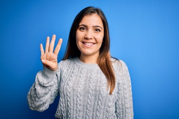 Sticker - Beautiful young woman wearing casual wool sweater standing over blue isolated background showing and pointing up with fingers number four while smiling confident and happy.