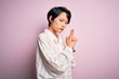 © Krakenimages.com - Young beautiful asian girl wearing casual shirt standing over isolated pink background Holding symbolic gun with hand gesture, playing killing shooting weapons, angry face
