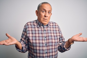 Canvas Print - Senior handsome man  wearing casual shirt standing over isolated white background clueless and confused expression with arms and hands raised. Doubt concept.