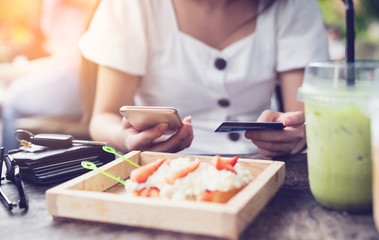 Wall Mural - Young woman making payment through mobile smart phone with credit card while shopping online in restaurant