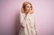 © Krakenimages.com - Middle age beautiful blonde woman wearing casual turtleneck sweater over pink background smelling something stinky and disgusting, intolerable smell, holding breath with fingers on nose. Bad smell
