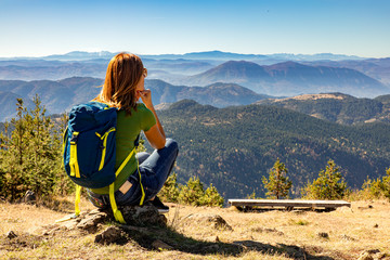 Wall Mural - female hiker with backpack sitting on top of the mountain and enjoying the view during the day.