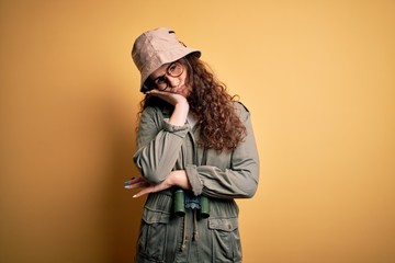 Poster - Young beautiful tourist woman on vacation wearing explorer hat and binoculars thinking looking tired and bored with depression problems with crossed arms.