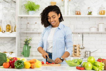 Beautiful young afro woman preparing vegetable salad