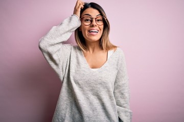 Poster - Young beautiful brunette woman wearing casual sweater and glasses over pink background confuse and wonder about question. Uncertain with doubt, thinking with hand on head. Pensive concept.