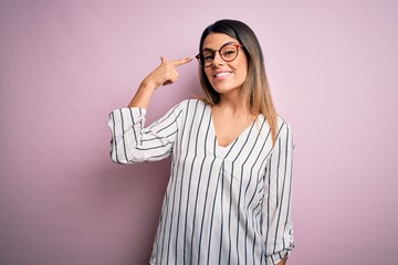 Sticker - Young beautiful woman wearing casual striped t-shirt and glasses over pink background Smiling pointing to head with one finger, great idea or thought, good memory