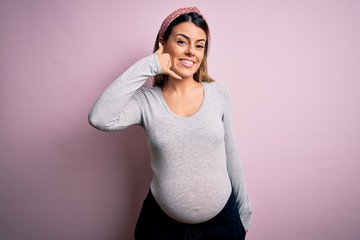 Sticker - Young beautiful brunette woman pregnant expecting baby over isolated pink background smiling doing phone gesture with hand and fingers like talking on the telephone. Communicating concepts.