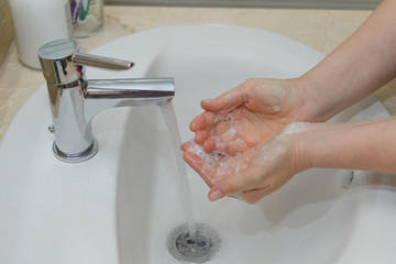 female hands in soapy foam under tap water close-up